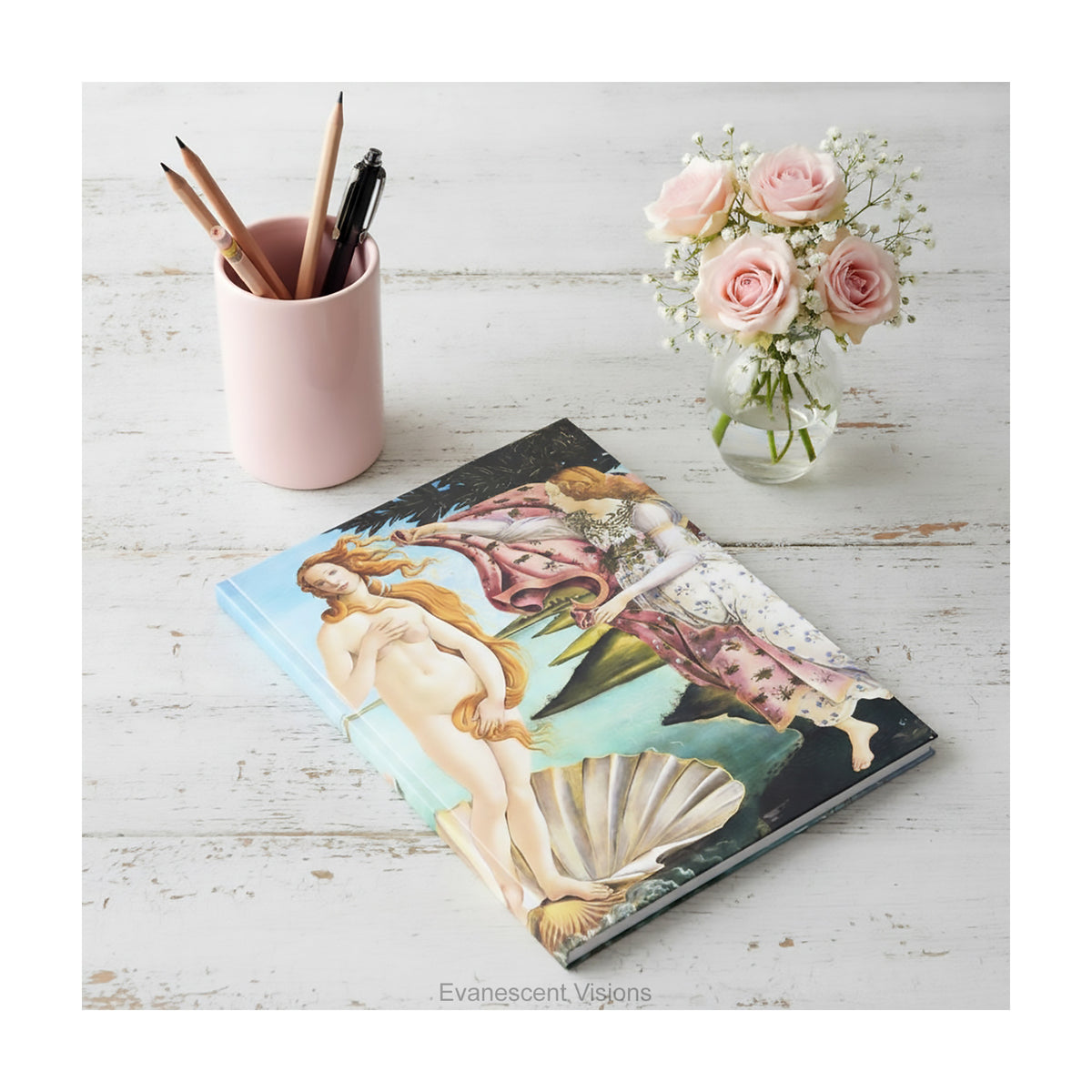 A hardcover featuring Sandro Botticelli's classic painting 'The Birth of Venus' displayed lying on a rustic white desk. 