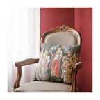 A square decorative cushion with a print of the classical painting 'La Primavera' by Sandro Botticelli, shown on an antique chair.