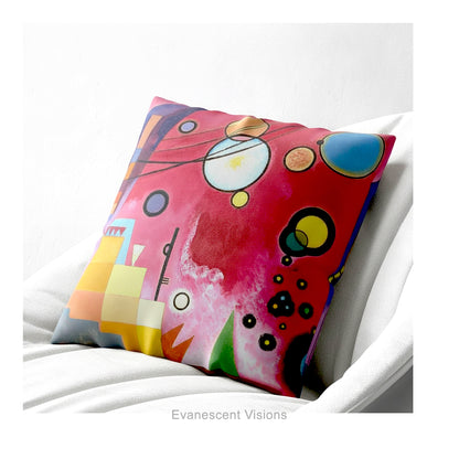 A colourful square cushion featuring an abstract art print of Schweres Rot (Heavy Red) by abstract artist Wassily Kandinsky, shown on a white armchair.