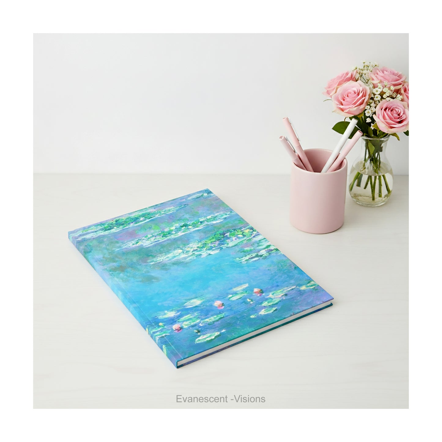 A hardback notebook printed with the   impressionist Water Lily painting in blues and greens by artist Claude Monet, shown on a desk top.