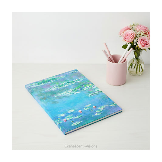 A hardback notebook printed with the   impressionist Water Lily painting in blues and greens by artist Claude Monet, shown on a desk top.