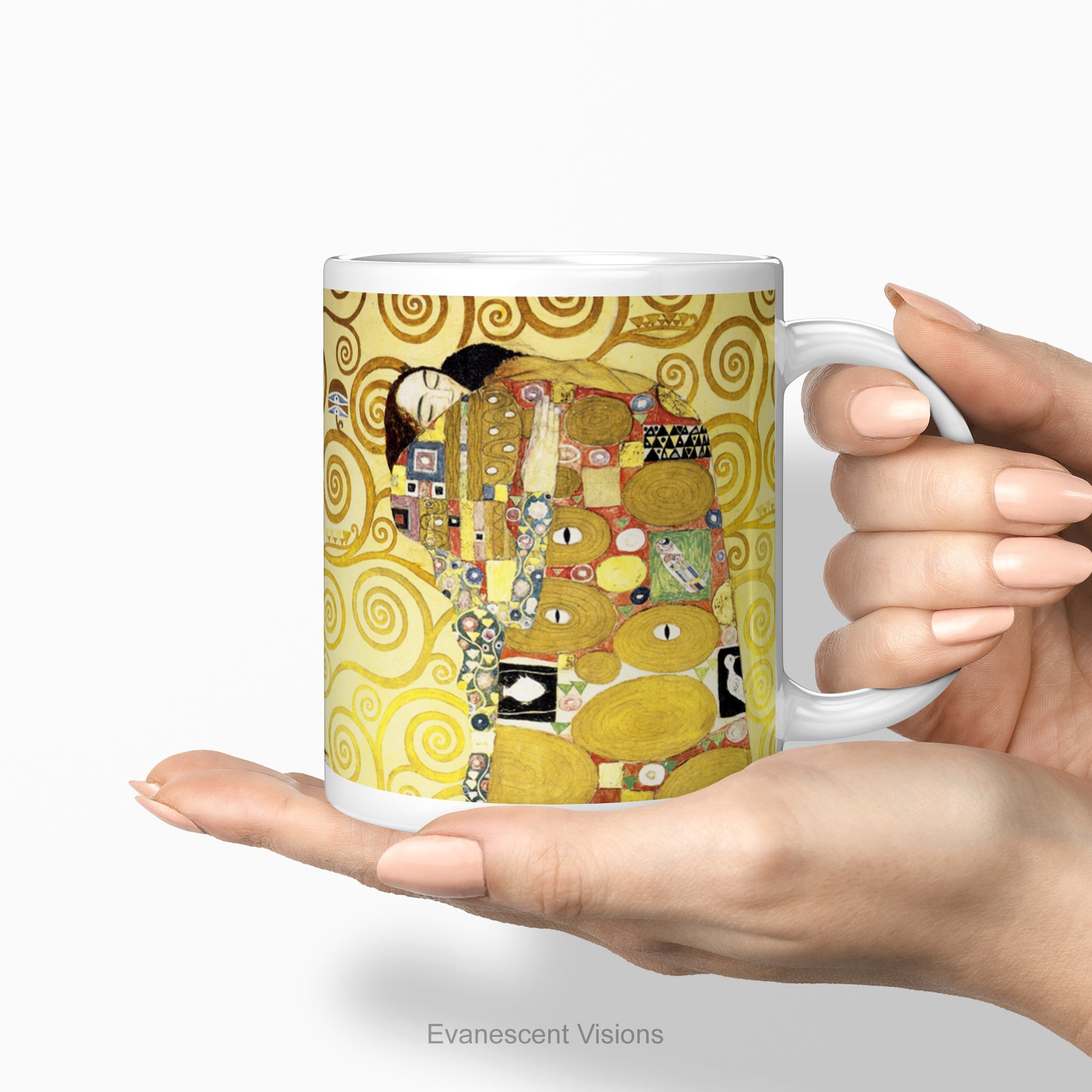 A hand holding  white ceramic mug featuring Gustav Klimt's 'The Embrace' artwork, shown standing against a  white background.