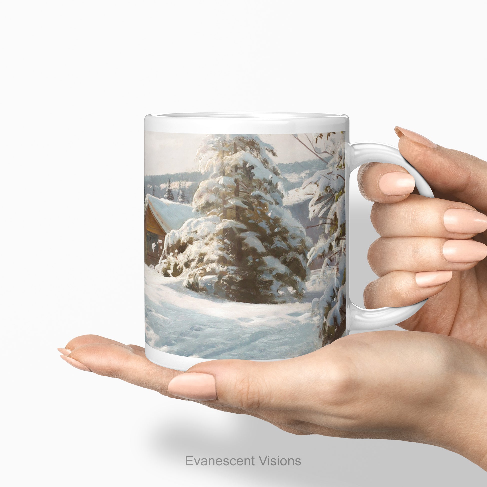 A white ceramic mug printed with a winter landscape scene of snow-covered pine trees, held in a person's hands against a light gray background. below.