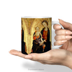 Hand holding a ceramic mug with a print of Renaissance painting 'Madonna and Child'. 