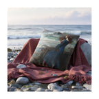 A decorative cushion featuring a print of the painting 'Miranda - The Tempest' by JW Waterhouse, shown on a red blanket on a rocky beach. 