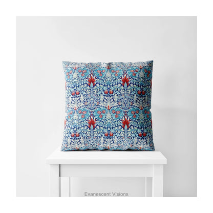 A square decorative cushion with red and blue floral  themed pattern entitled 'Snakeshead' by William Morris, on a white stool. 
