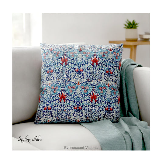 A square decorative cushion with red and blue floral  themed pattern entitled 'Snakeshead' by William Morris, on cream coloured sofa