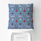 A square  cushion with a print of William Morris pattern Snakeshead, shown standing on a white stool. 
