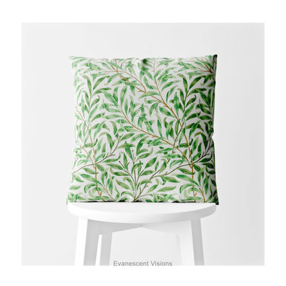 A square decorative cushion with green botanical pattern titled 'Willow Bough' by William Morris, on a white stool. 
