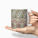Hands holding a ceramic mug featuring print of floral design  'Corncockle' by William Morris.