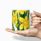 Hands holding a ceramic mug with a print of painting of 'Spring Daffodil Flowers'